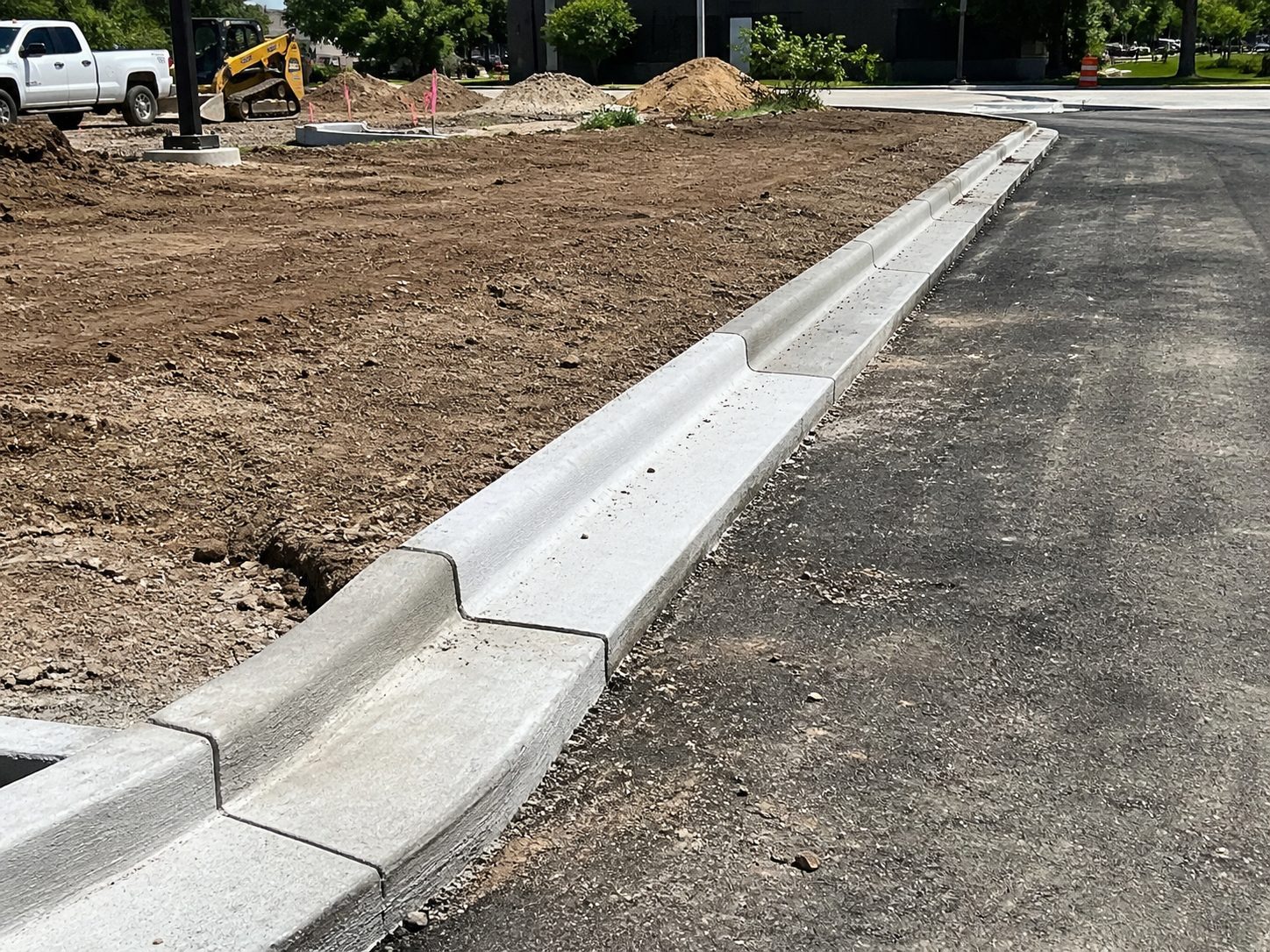 Fresh concrete curb installation in progress at a commercial property construction site