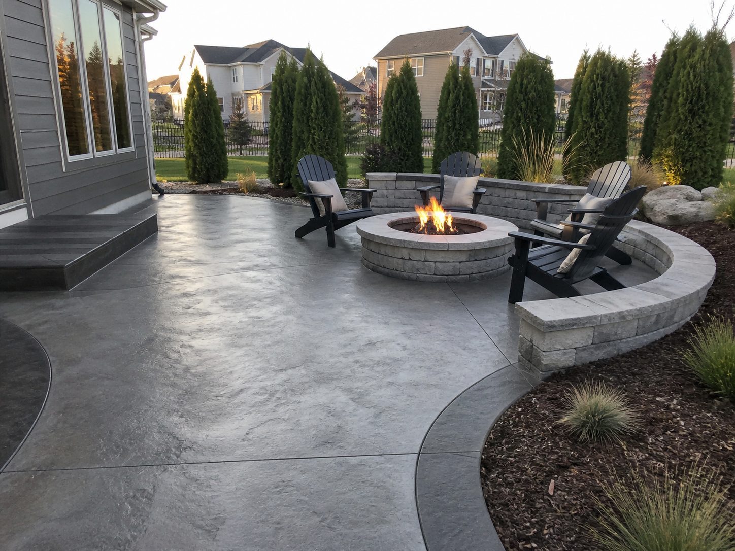 Stamped concrete patio with Adirondack chairs and fire pit at a residential property