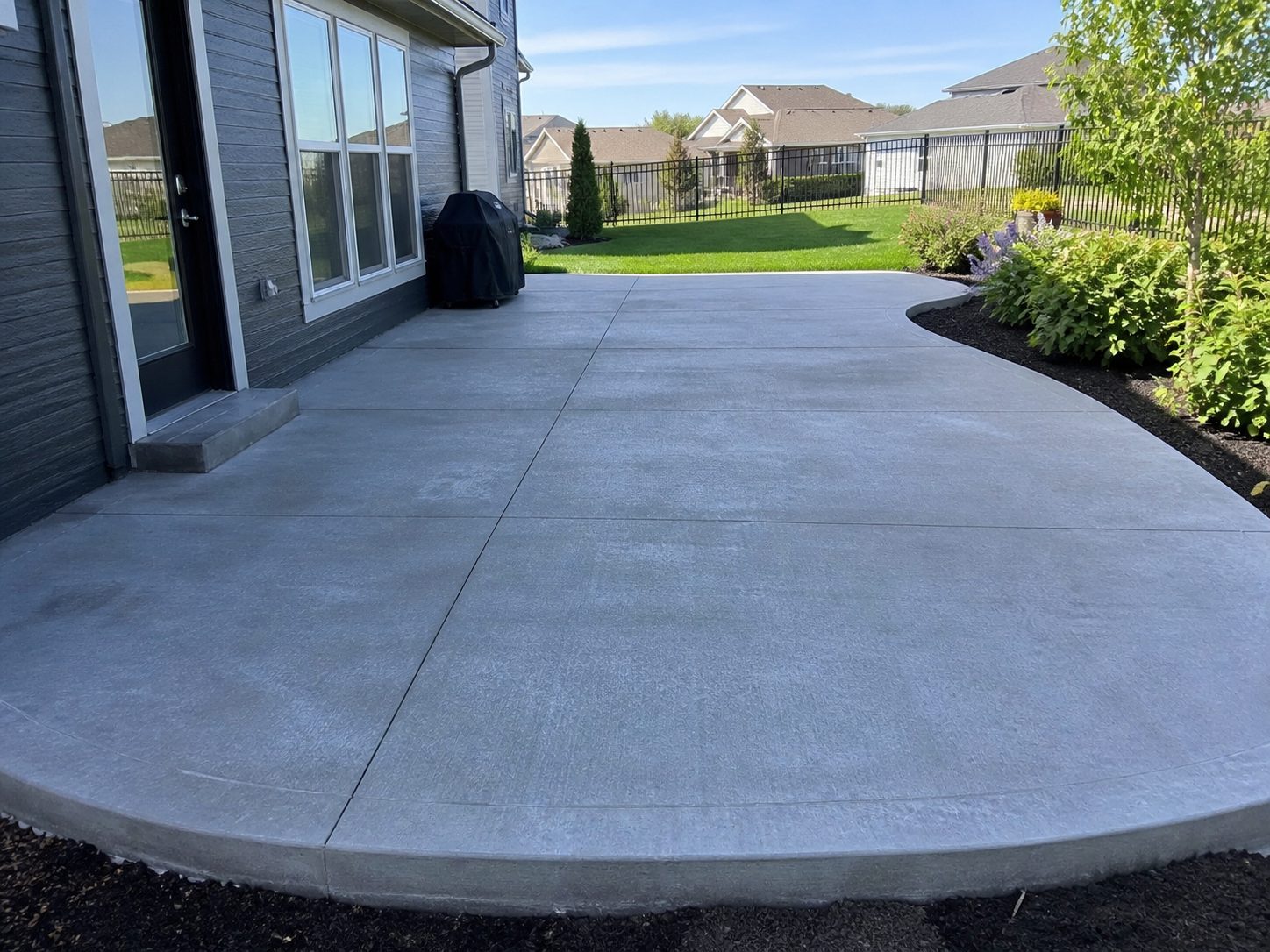 Finished residential concrete backyard patio in the Kansas City metro — clean broom finish with outdoor living setup