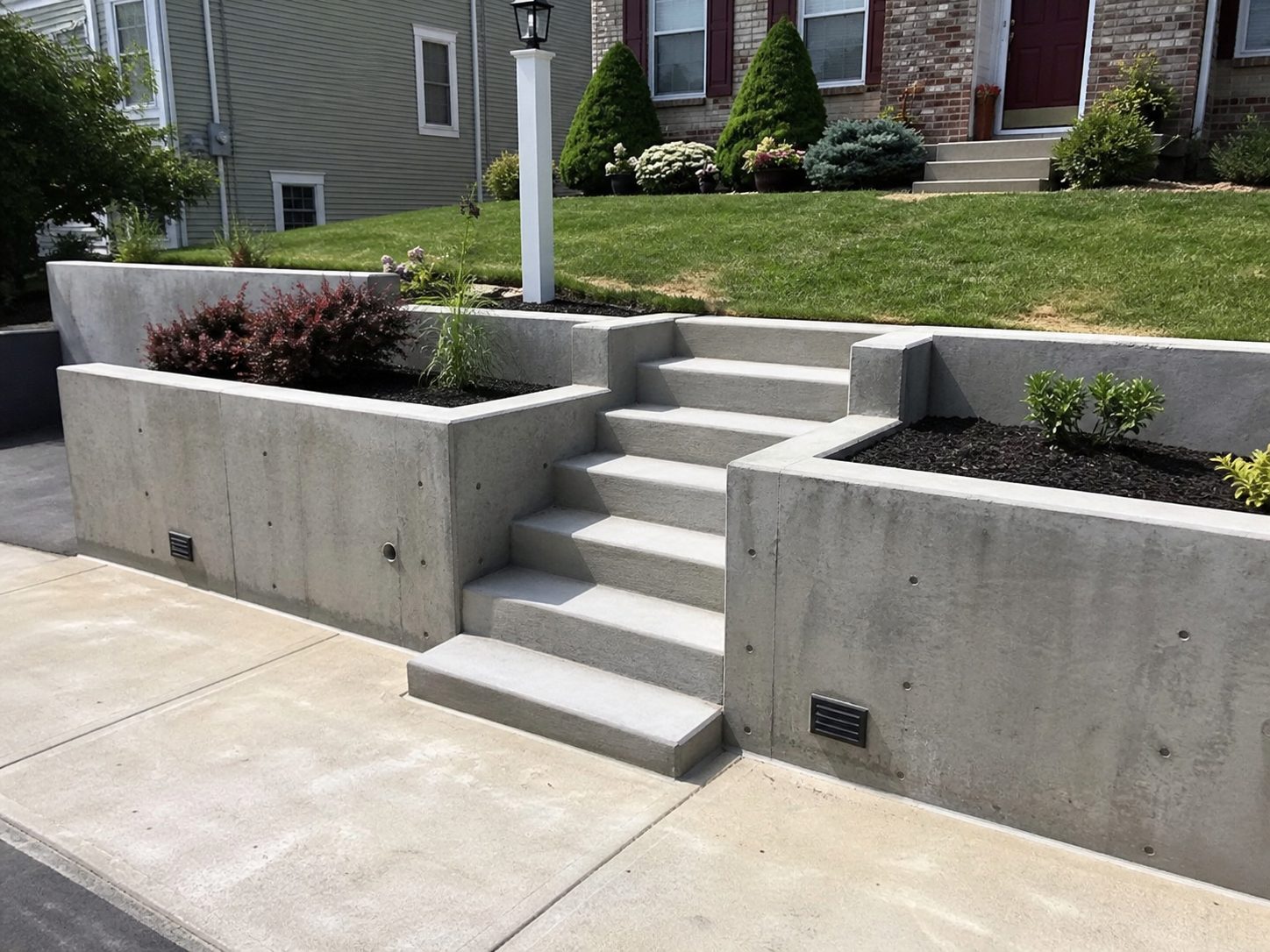 Finished concrete retaining wall with integrated steps and landscaping at a Lee's Summit, MO residential property